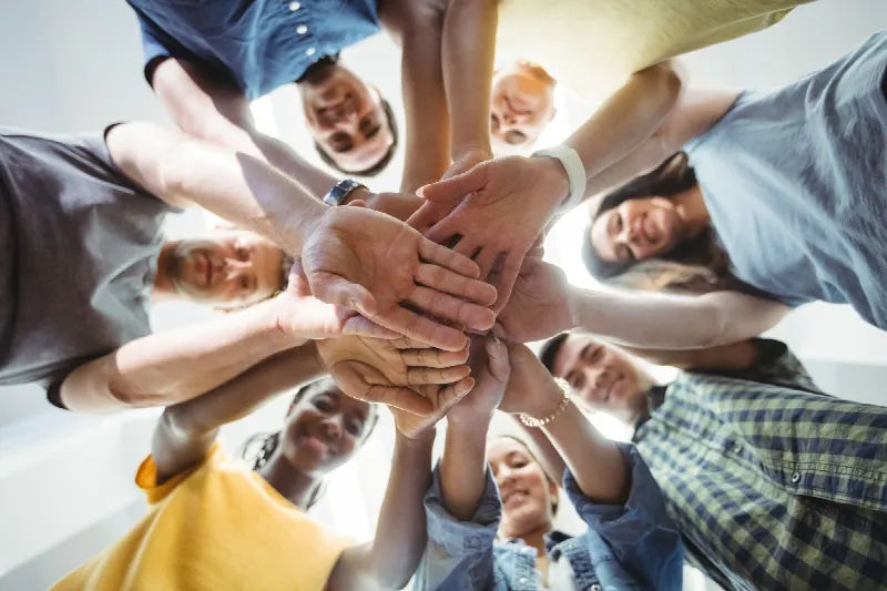 Een groep mensen legt de handen op elkaar in een kring