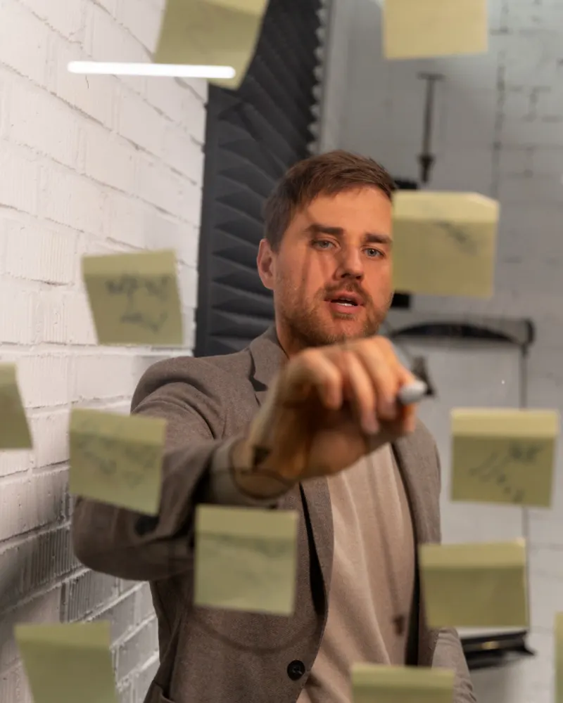 Een man plakt notities op een glazen wand en zet de planning op een rij
